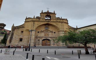 Photo of aerial view of Bilbao, Spain city downtown with a Nevion River, Zubizuri Bridge and promenade. Mountain at the background, with clear blue sky.