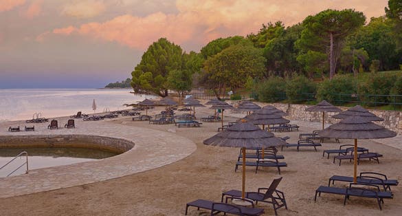 Photo of Beach and resort with beach chairs and umbrellas in morning light on the beach of a Croatian seaside holiday resort in Porec.