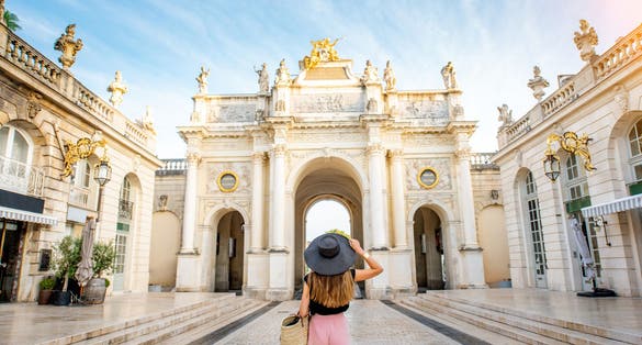 Photo of young woman tourist enjoying beautiful triumphal arch traveling in Nancy city in France.