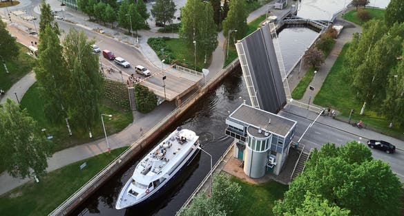 Aerial view of the canal in Joensuu, Finland. The ship passes the lock on the canal. The bridge over the canal is raised.