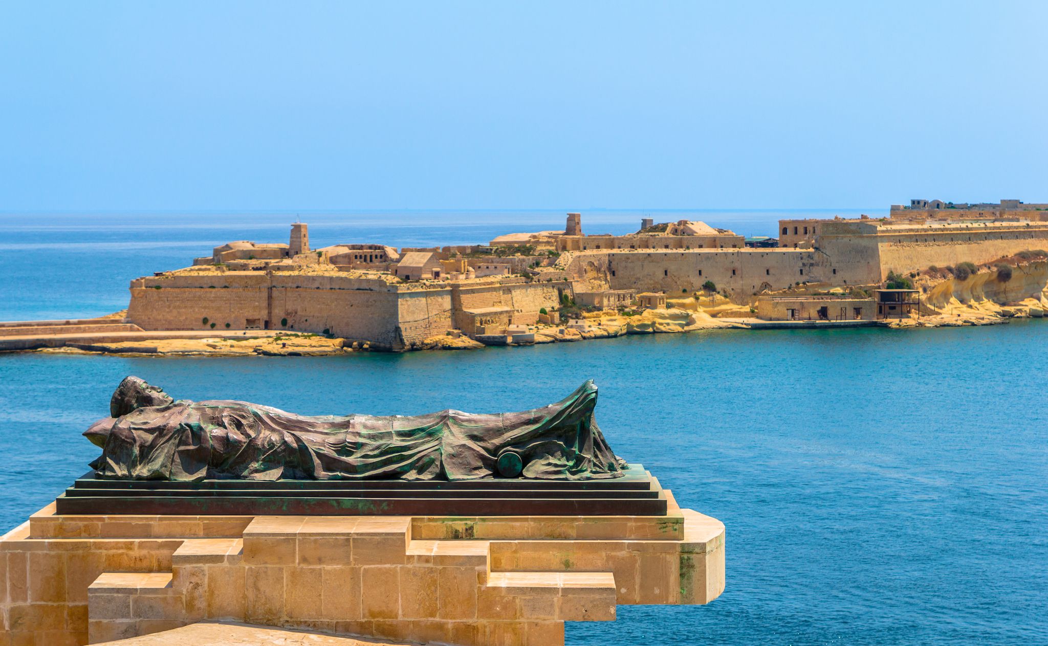 The Siege Bell monument with Fort Ricasoli in the background.
