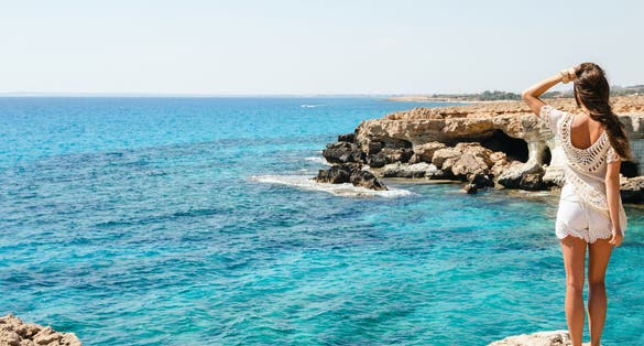 Photo of young woman looking on the stunning views from the famous Cape Greco viewpoint, Cyprus.