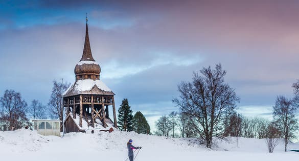 photo of a girl skiing in front of Frösö Church in winter in Sweden.