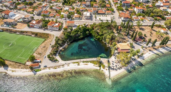 Aerial drone view of Karavomilos lake in Sami town, Kefalonia island, Greece. Ionian sea coast with beautiful beach, turquoise sea water and karst lake Karavomilos with crystal clear water.