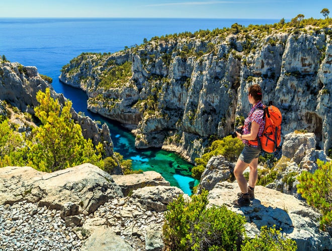 Hiker overlooking Calanque d’En-Vau near Marseille, France, with turquoise water, limestone cliffs, and Mediterranean coastline..jpg