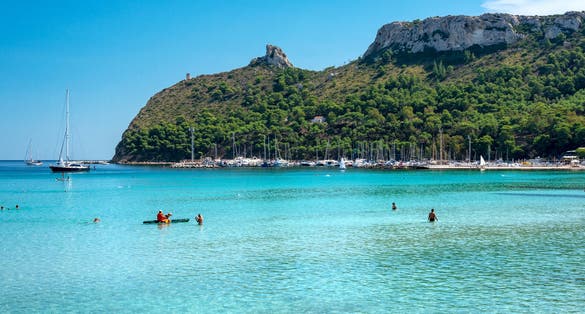 Poetto beach, crystal clear water and the famous Sella del Diavolo, Cagliari, Sardinia, Italy.