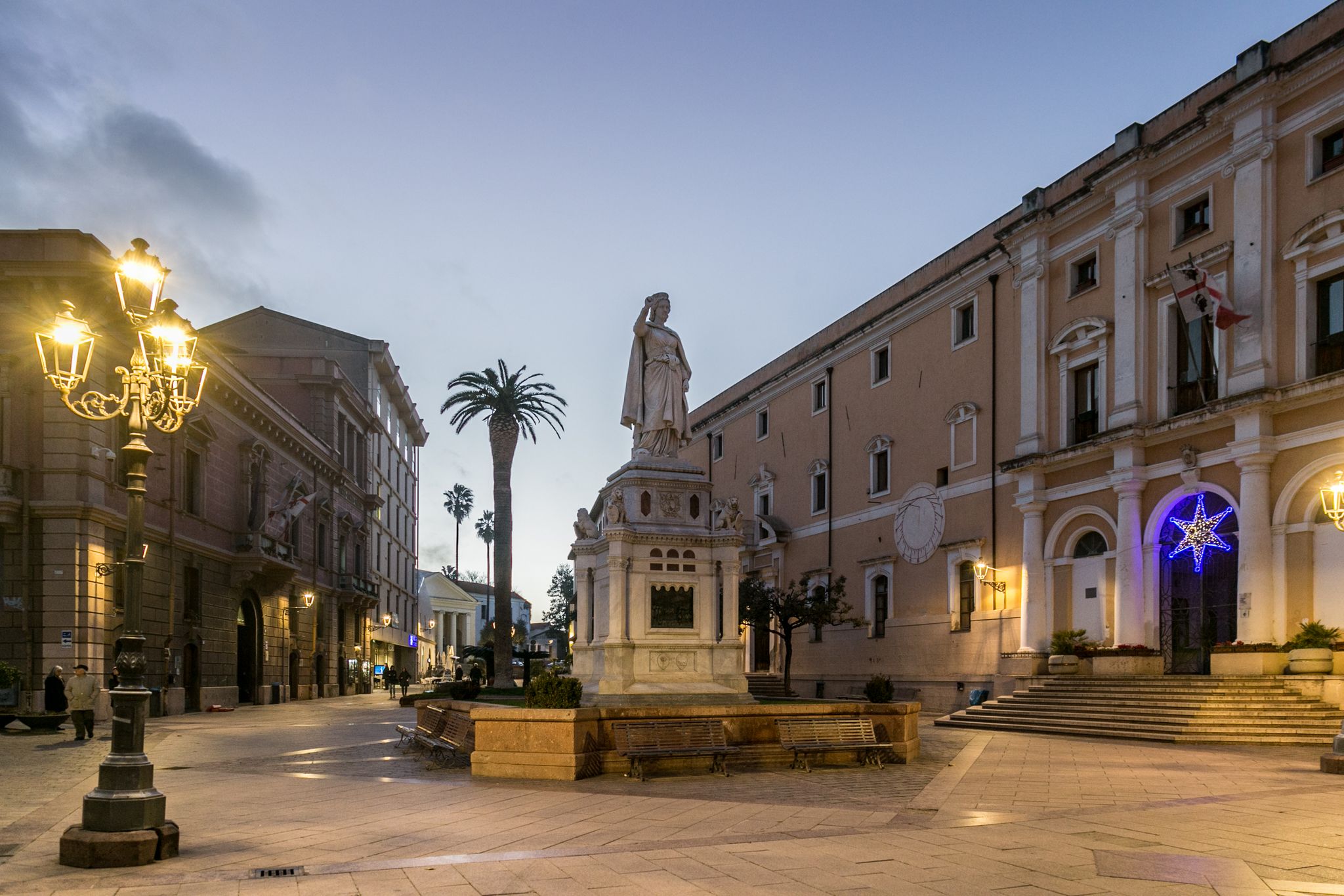 photo of a statue, lamp post and buildings Olbia at night, Sardinia ,Italy.