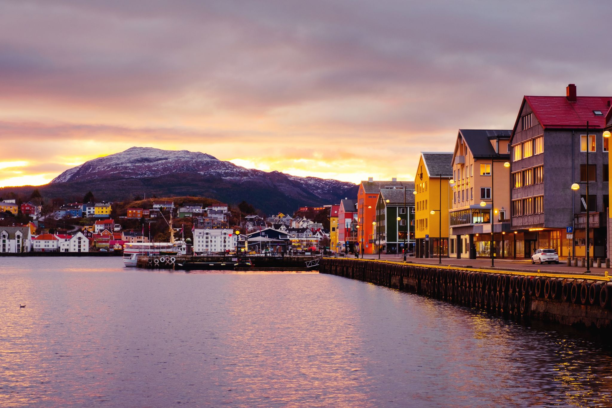 photo of view of Kristiansund, Norway. View of city center of Kristiansund, Norway during the cloudy morning at sunrise with colorful sky. Port with historical buildings.
