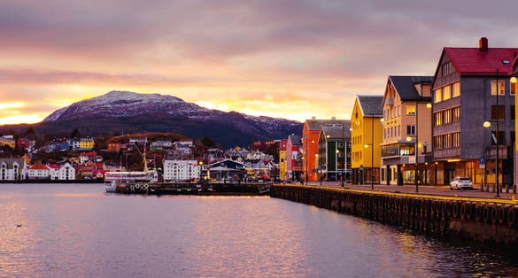 photo of view of Kristiansund, Norway. View of city center of Kristiansund, Norway during the cloudy morning at sunrise with colorful sky. Port with historical buildings.