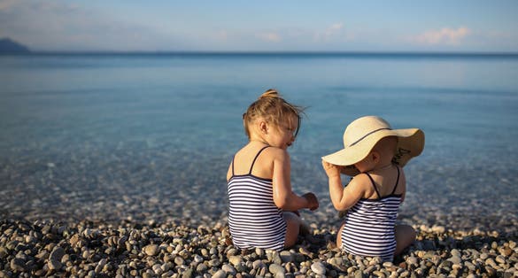 Photo of the baby playing with her sister on the beach in Kemer, Turkey. Concept vacation with children.