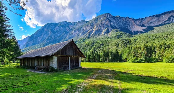 An abandoned hut with a scenic view on mount Dobratsch in the natural park Dobratsch in Villach, Carinthia, Austria. Gailtaler and Villacher Alps. Lush green alpine meadow. Breathing. Remote Location