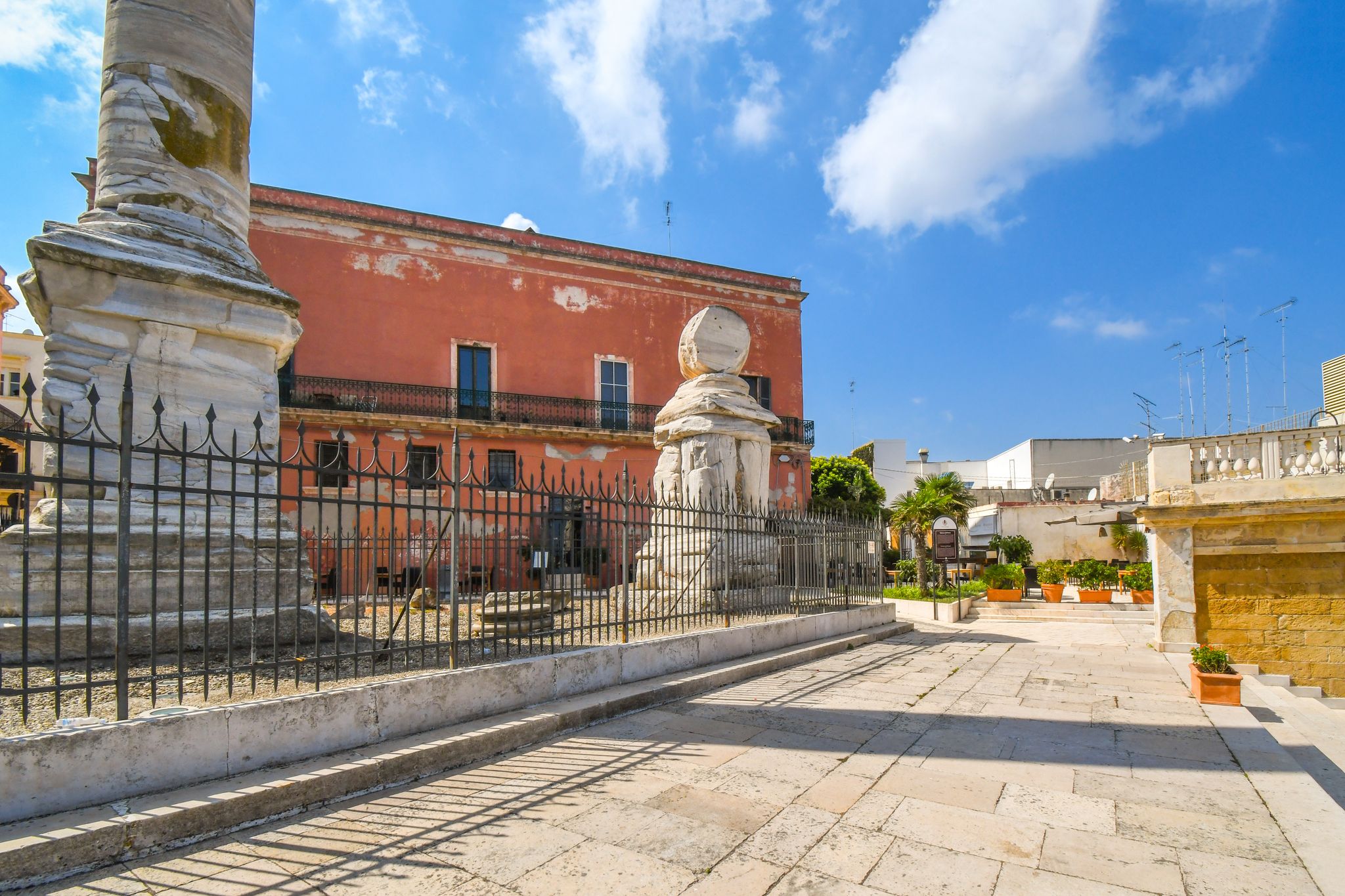 Fenced ancient ruins atop the promenade steps to the Colonne Romane or Roman Column in the port city of Brindisi Italy in the Puglia Region