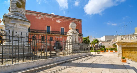 Fenced ancient ruins atop the promenade steps to the Colonne Romane or Roman Column in the port city of Brindisi Italy in the Puglia Region