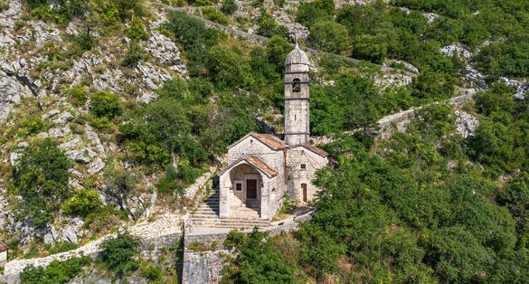 Photo of Aerial view of the Church of Our Lady of Remedy, perched on the slope of St. John Mountain above the old town of Kotor in Montenegro.