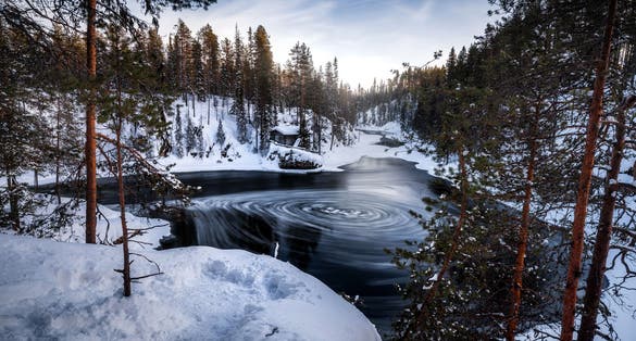 Photo of Myllykoski watermill at Pieni Karhunkierros hiking trail during cold and wintery day with rapids flowing in Finland.