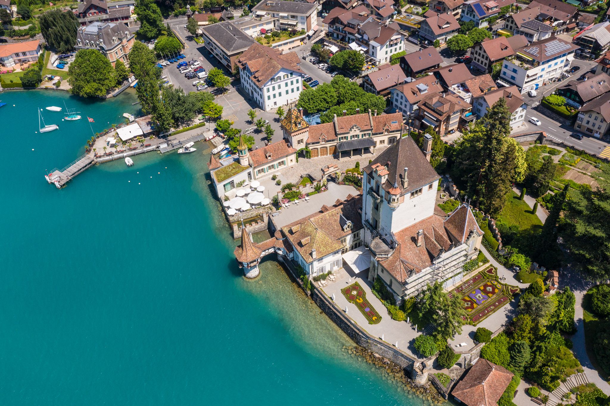 photo of aerial view of the famous Oberhofen village by lake Thun with its famous castle in Canton Bern in Switzerland on a sunny summer day.