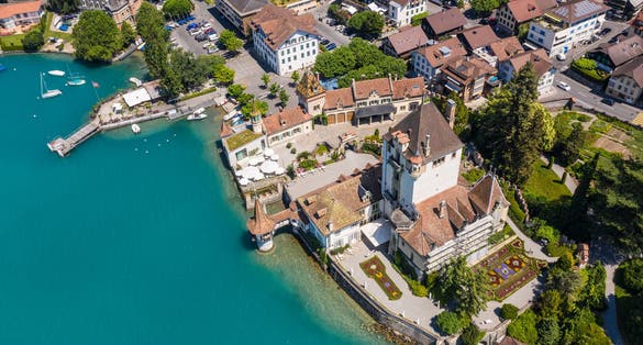 photo of aerial view of the famous Oberhofen village by lake Thun with its famous castle in Canton Bern in Switzerland on a sunny summer day.
