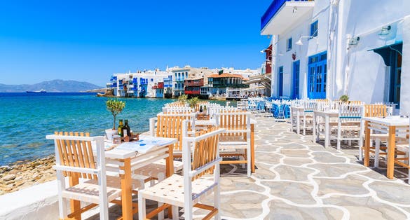 Photo of chairs with tables in typical Greek tavern in Little Venice part of Mykonos town, Mykonos island, Greece.