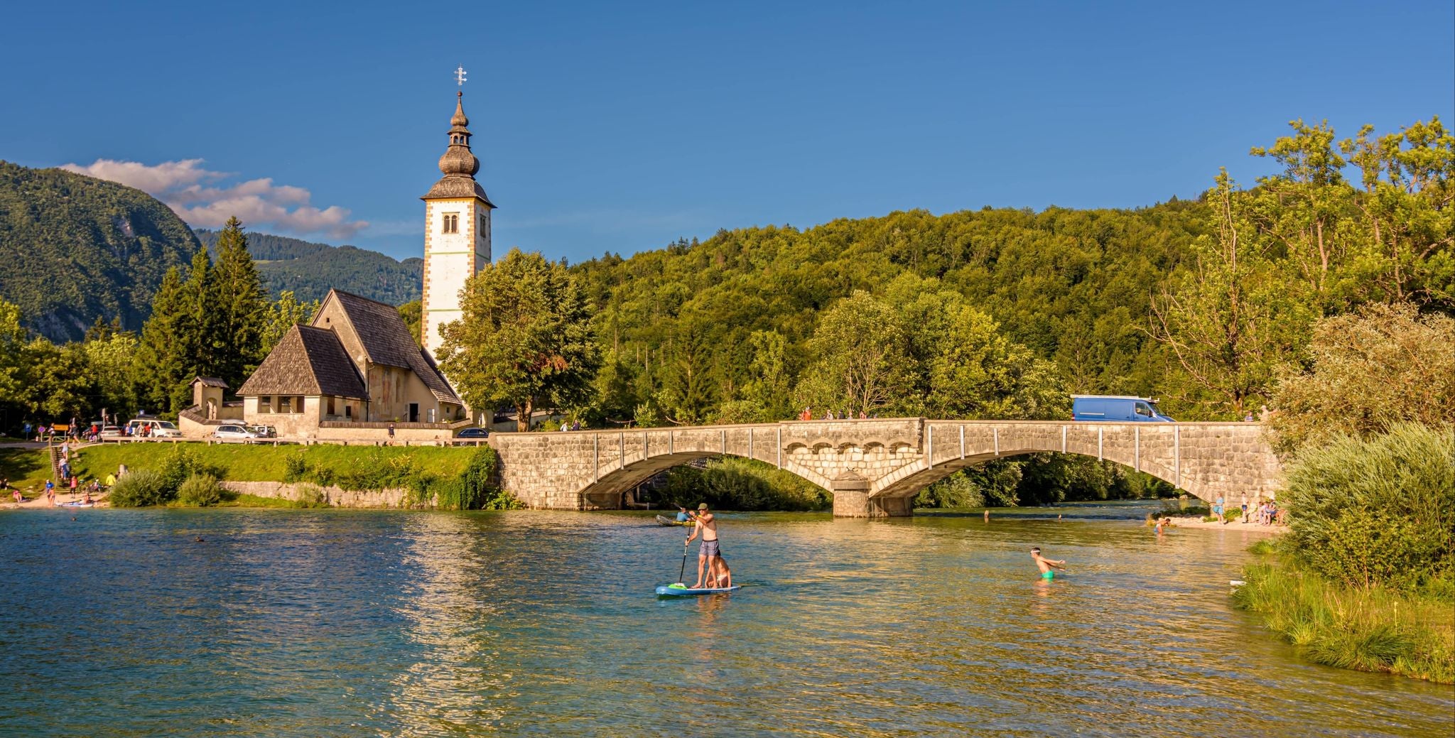 Paddleboarders on Lake Bohinj with St. John the Baptist Church and stone bridge in the background, Slovenia..jpg
