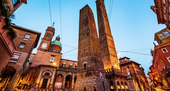 photo of Two famous falling Bologna towers Asinelli and Garisenda. Evening view, long exposure. Bologna, Emilia-Romagna, Italy.
