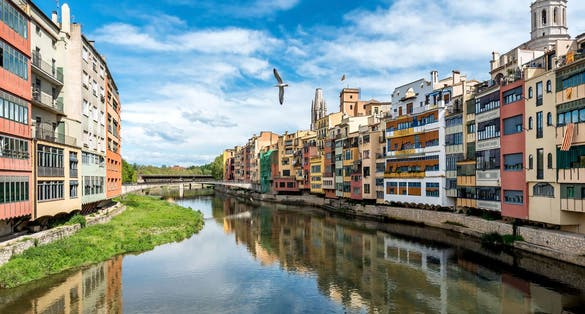 photo of wide-angle colorful yellow and orange houses and famous house Casa Maso reflected in water river Onyar, in Girona, Catalonia, Spain.