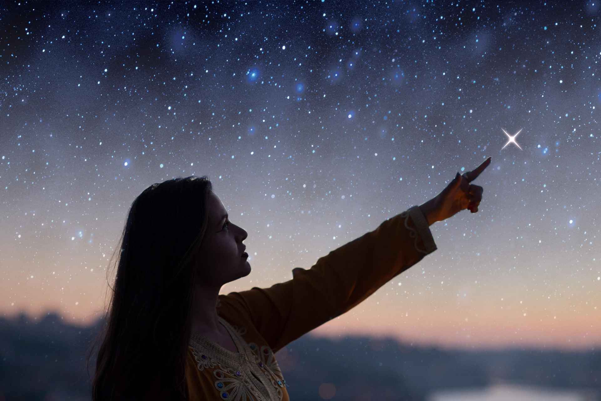 A woman is stargazing at Mt. Teide, pointing at a bright star in the night sky with a sunset in the background..jpg