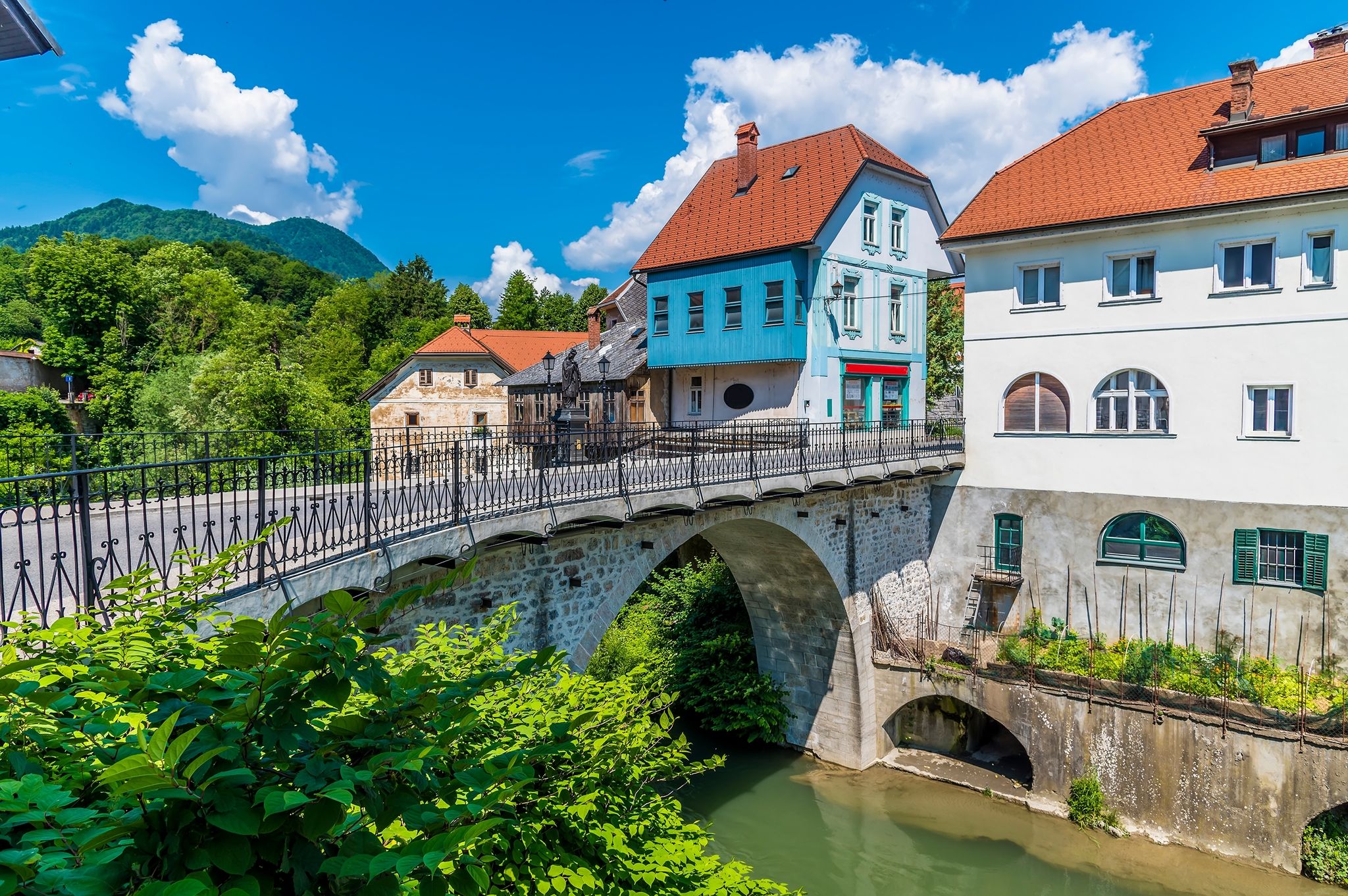 Photo of A view towards the fourteenth century Capuchin Bridge and buildings beside the Selca Sora River in Skofja Loka, Slovenia in summertime.