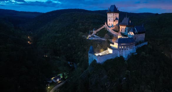 Photo of aerial, night view on Karlstejn Castle, Burg Karlstein, large Gothic castle near Prague illuminated by floodlights, Czech Republic.