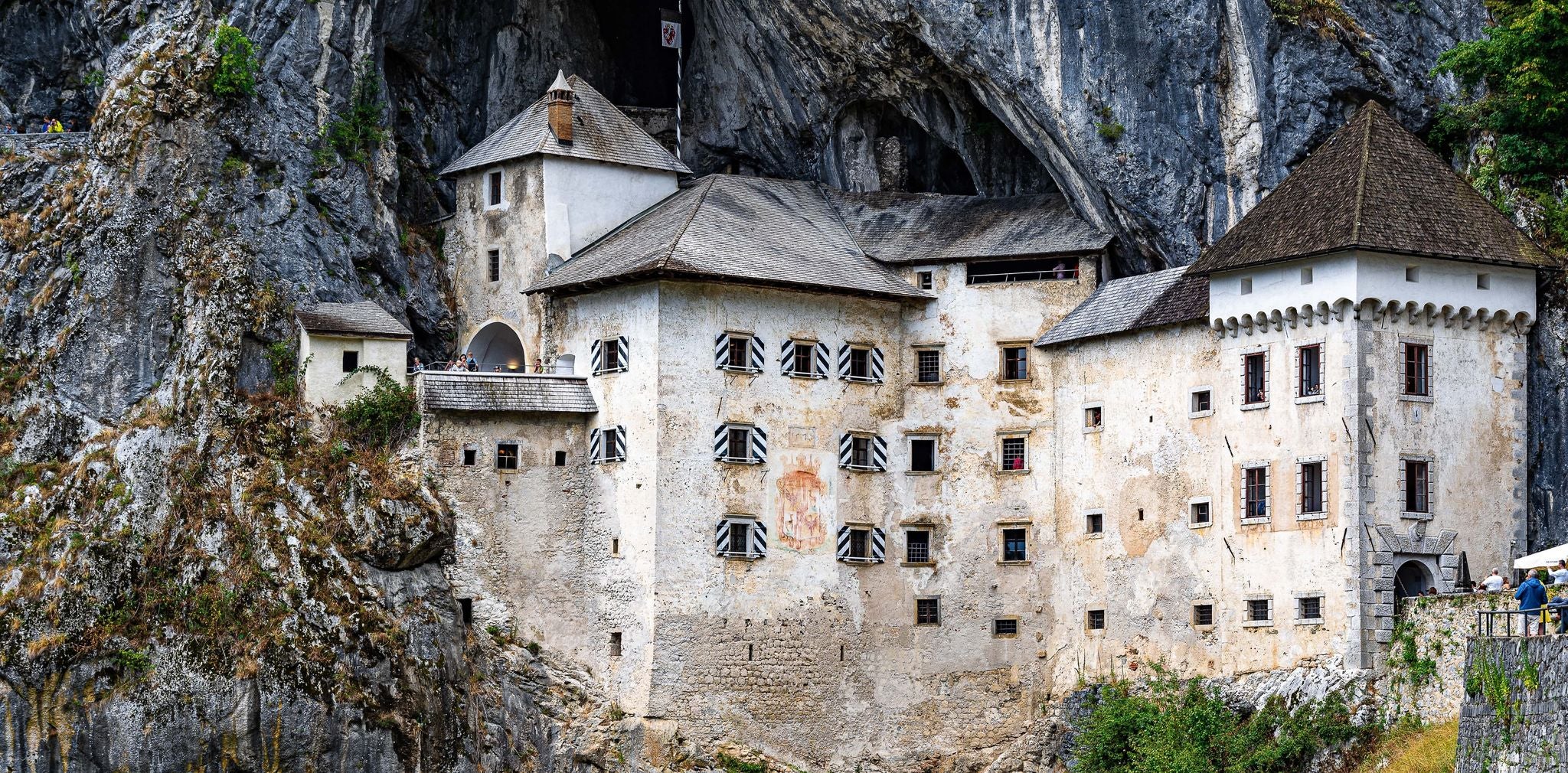 Predjama Castle built into a cliffside in southwestern Slovenia, surrounded by rocky terrain and greenery..jpg