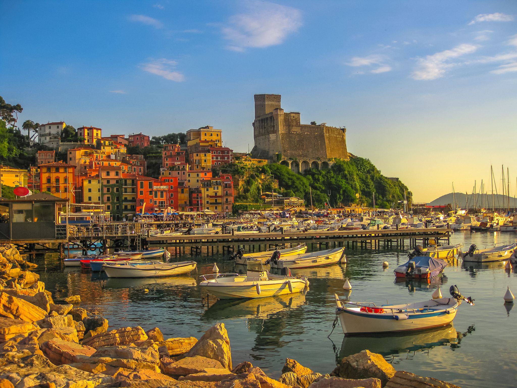 San Giorgio castle of Lerici town from the of Gulf of Poets with sailing boats and motor boats at sunset. La Spezia province, Ligurian Coast of Italy. Scenic Lerici Port with pedestrian jetty.