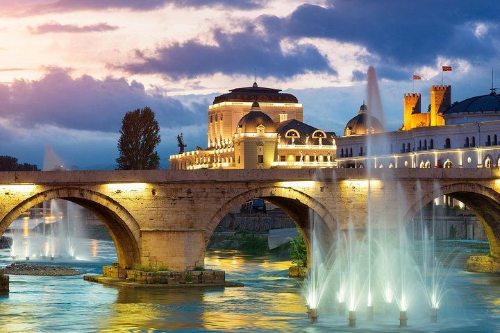 The Stone Bridge in Skopje, North Macedonia, is lit up at night with fountains and historic buildings in the background..jpg