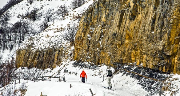 Schia, Parma, Italy - Two man practicing alpine ski near a vertical snow capped rock mountain