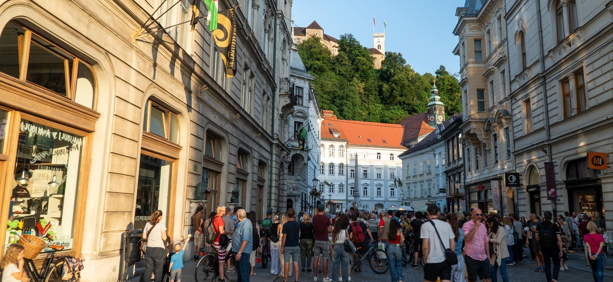 Crowds walking along a lively street in Ljubljana with Ljubljana Castle visible on the hill in the background..jpg