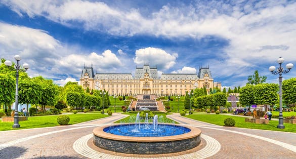 Photo of water fountain in central square in Iasi town, Cultural Palace in background, Moldavia, Romania.