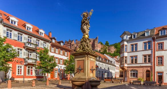 photo of view of The Madonna statue in Kornmarkt square and castle in Heidelberg by day, Germany.
