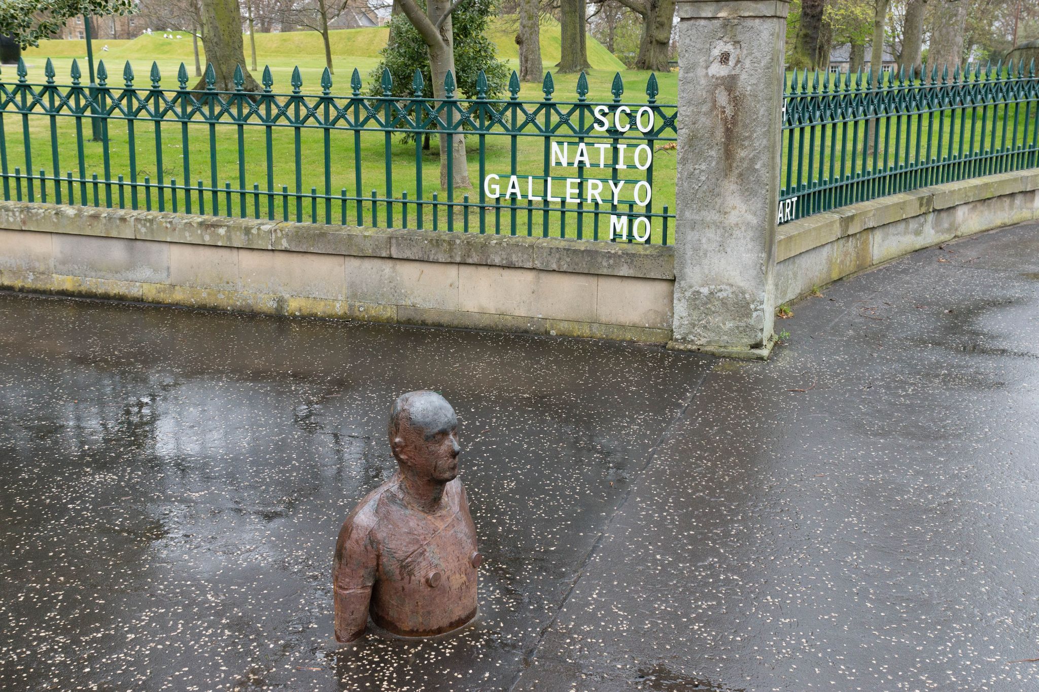 Sculpture of a man buried in the ground in front of the Scottish National Gallery of Modern Art in Edinburgh, UK. Edinburgh is the most popular tourist destination in Scotland.