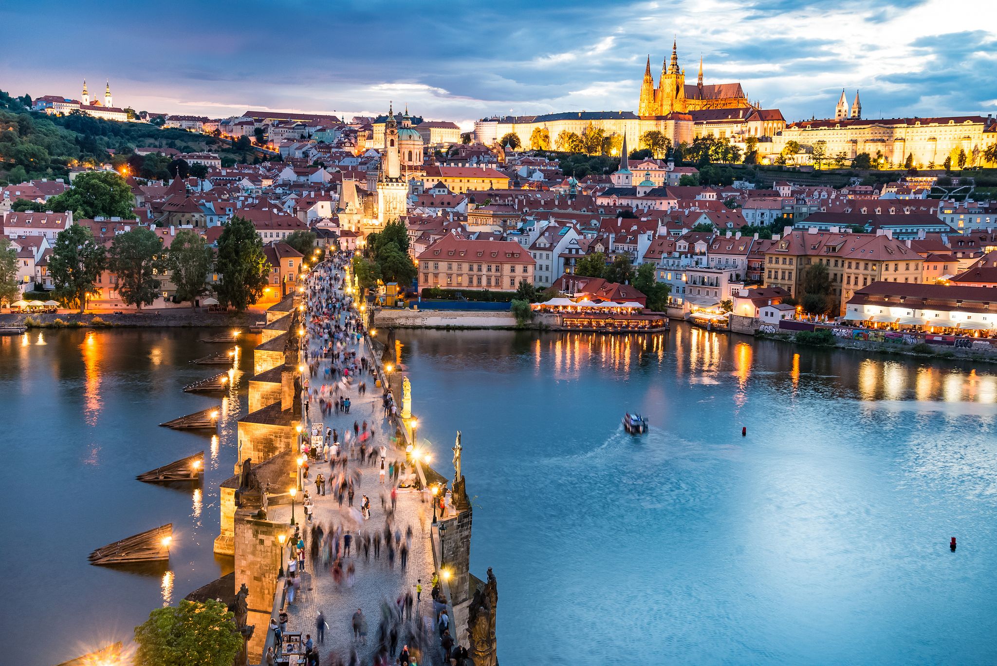 Photo of panorama of Prague with red roofs and Charles Bridge from above summer day at dusk, Czech Republic.