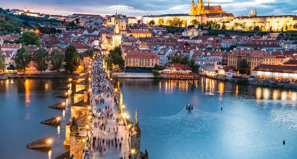 Photo of panorama of Prague with red roofs and Charles Bridge from above summer day at dusk, Czech Republic.