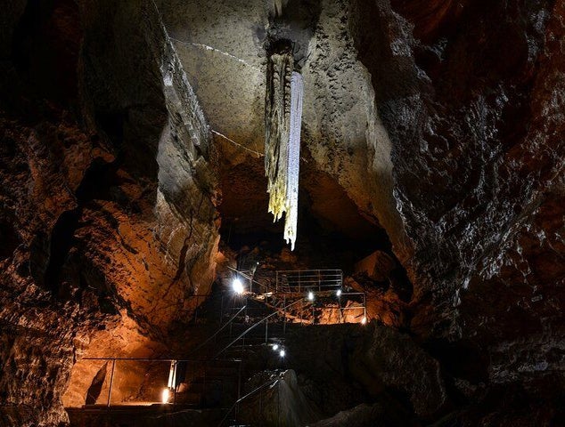 A lit pathway inside a cave in Ireland, featuring a large stalactite hanging from the rocky ceiling..jpg