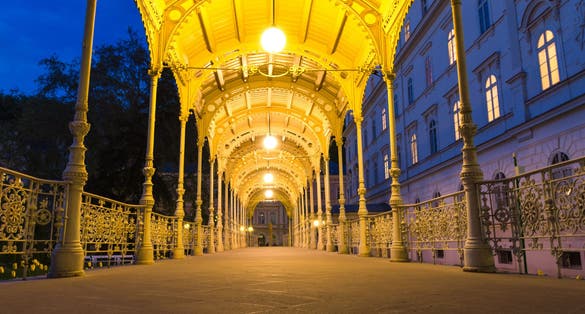 Photo of park Colonnade with wooden arbor and lights in Dvorak Park Dvorakovy sady in Karlovy Vary (Carlsbad) historical city centre, evening twilight view, West Bohemia, Czech Republic.