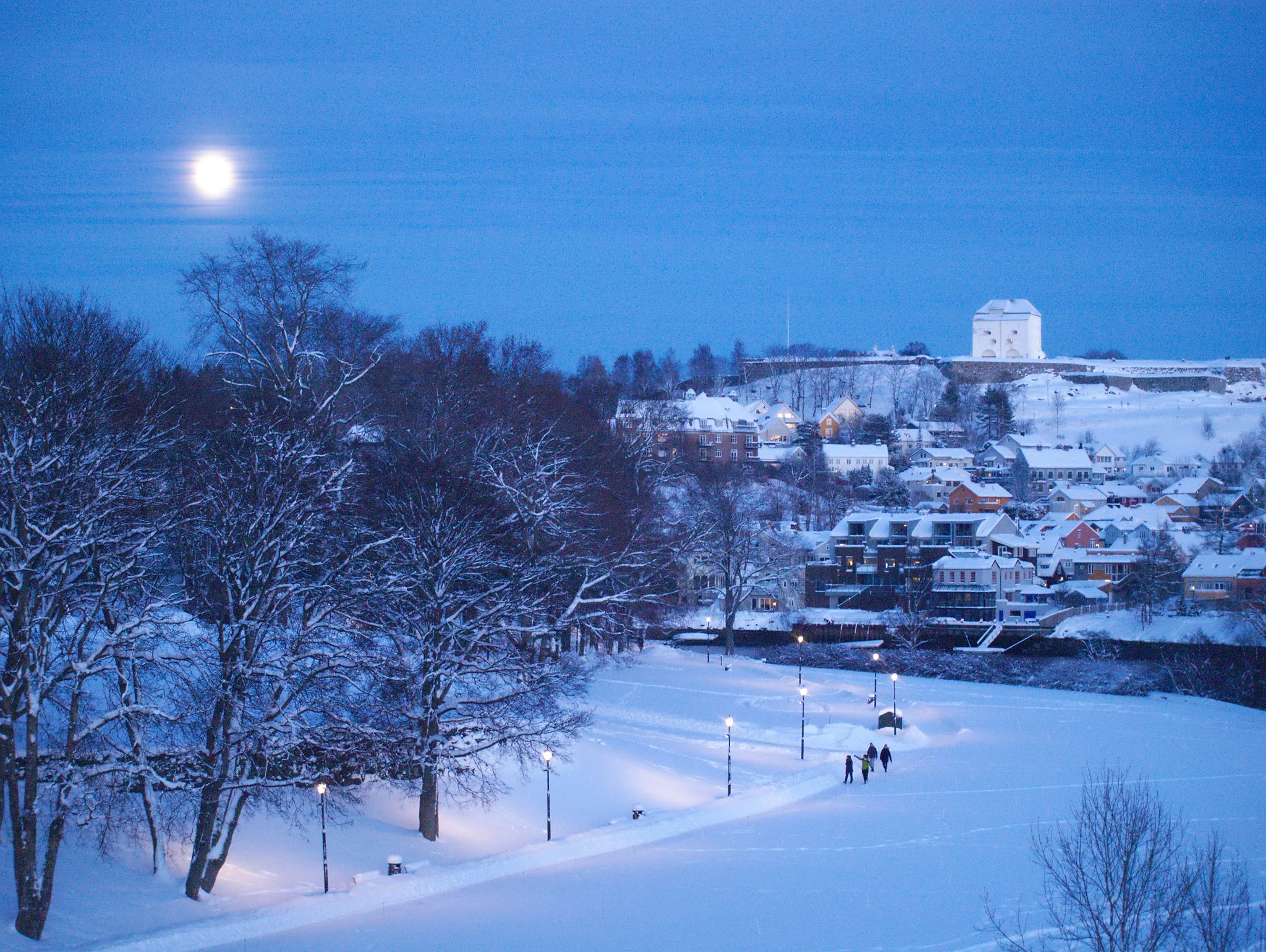 Winter view to the Kristiansten Fortress and Nidelva River in Trondheim, Norway. Full moon above the town.