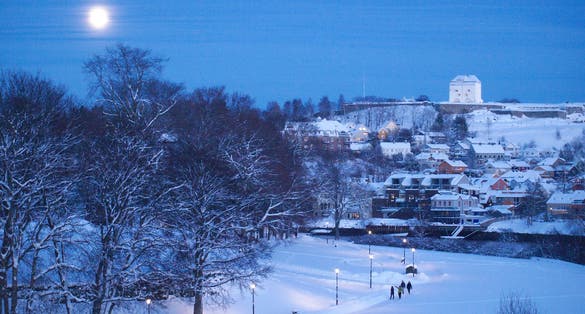 Winter view to the Kristiansten Fortress and Nidelva River in Trondheim, Norway. Full moon above the town.