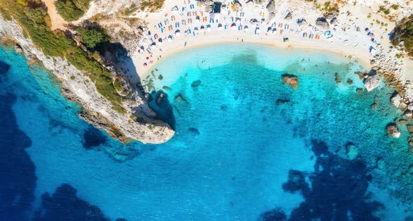 Photo of aerial view of Porto Katsiki blue sea, rock, sandy beach with umbrellas at sunrise in summer, Lefkada island, Greece. 