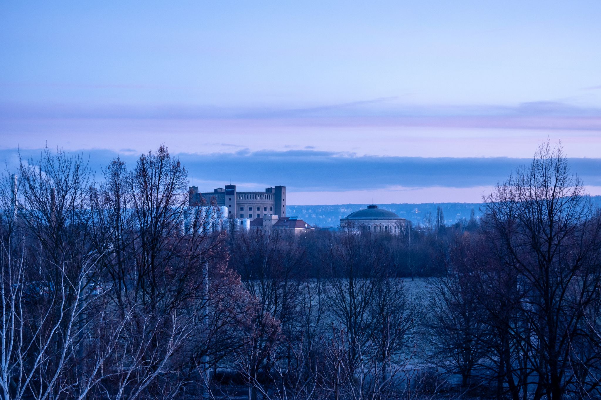 Typical landmarks of Dresden, Saxony: Panometer and Gasometer in front of a a colorful sky, viewed from a distance.