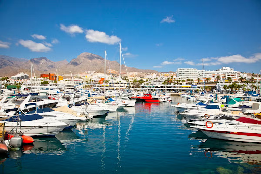 Luxury yachts docked in Puerto Colon marina, with mountain views and resorts in Costa Adeje, Tenerife, Canary Islands..png