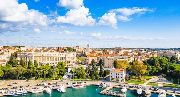 Photo of aerial view of city of Pula, ancient Roman arena, historic amphitheater and harbor with ships, Croatia.