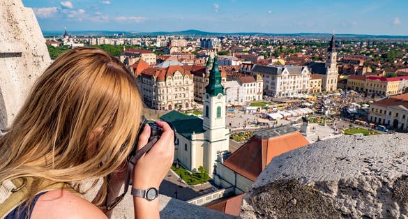 Woman tourist taking pictures of Oradea city main square.