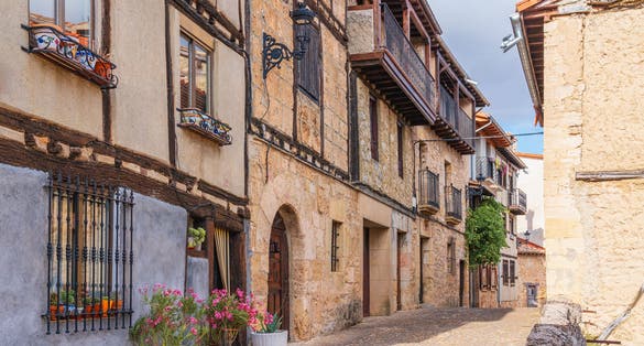 photo of view of Picturesque street showcasing traditional buildings decorated with flowers in a rural town. Frías, Burgos Province, Spain