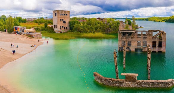 Photo of aerial view of the Rummu abandoned prison Tallinn Estonia lake beach, beautiful view of the forest, lake and old prison remains most of which are under water.