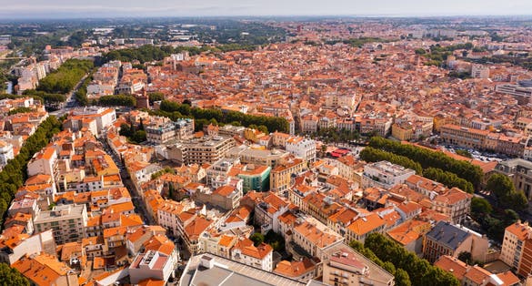 Photo of aerial view of Perpignan, France. Red rooftops of residential buildings visible from above.